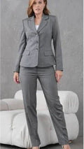 Woman wearing a gray suit standing against a neutral background