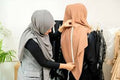 Lady measuring a woman wearing abaya during alteration.
