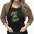 Person wearing a black apron with 'Love is in the Hair' text on a white background