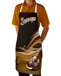 A person wearing a black apron with white straps and a brown and gold chocolate swirl graphic, featuring the word 'Swoops' in white script with a red outline across the chest. The person is also wearing a mustard yellow polo shirt, shown against a plain white background.