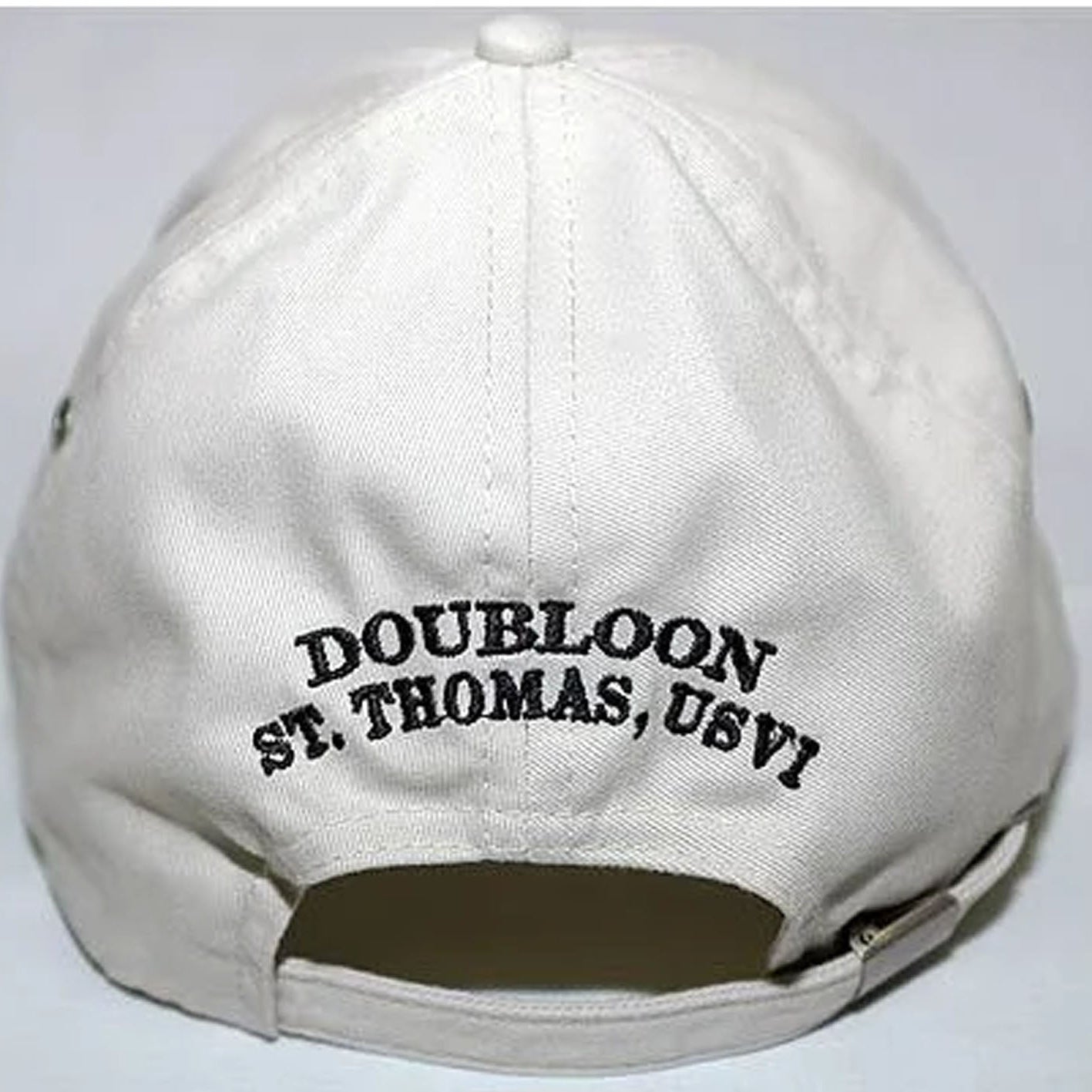 An off-white baseball cap shown from the back, featuring black embroidered text that reads 'DOUBLOON ST. THOMAS, USVI'.