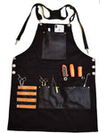 A black multi-pocket work apron with adjustable shoulder straps and metal snap buttons, shown flat-laid on a white background with various hand tools tucked into its pockets.