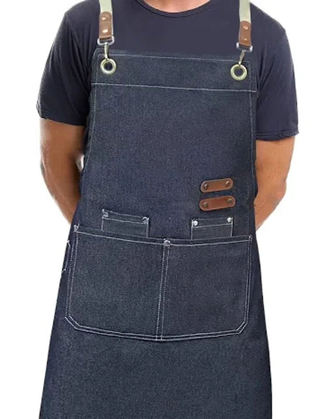 A person wearing a dark indigo denim bib apron with brown leather strap accents and metal grommets, shown against a plain white background.