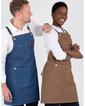 Two models wearing aprons, one in blue denim and one in brown canvas, standing against a light gray studio background.