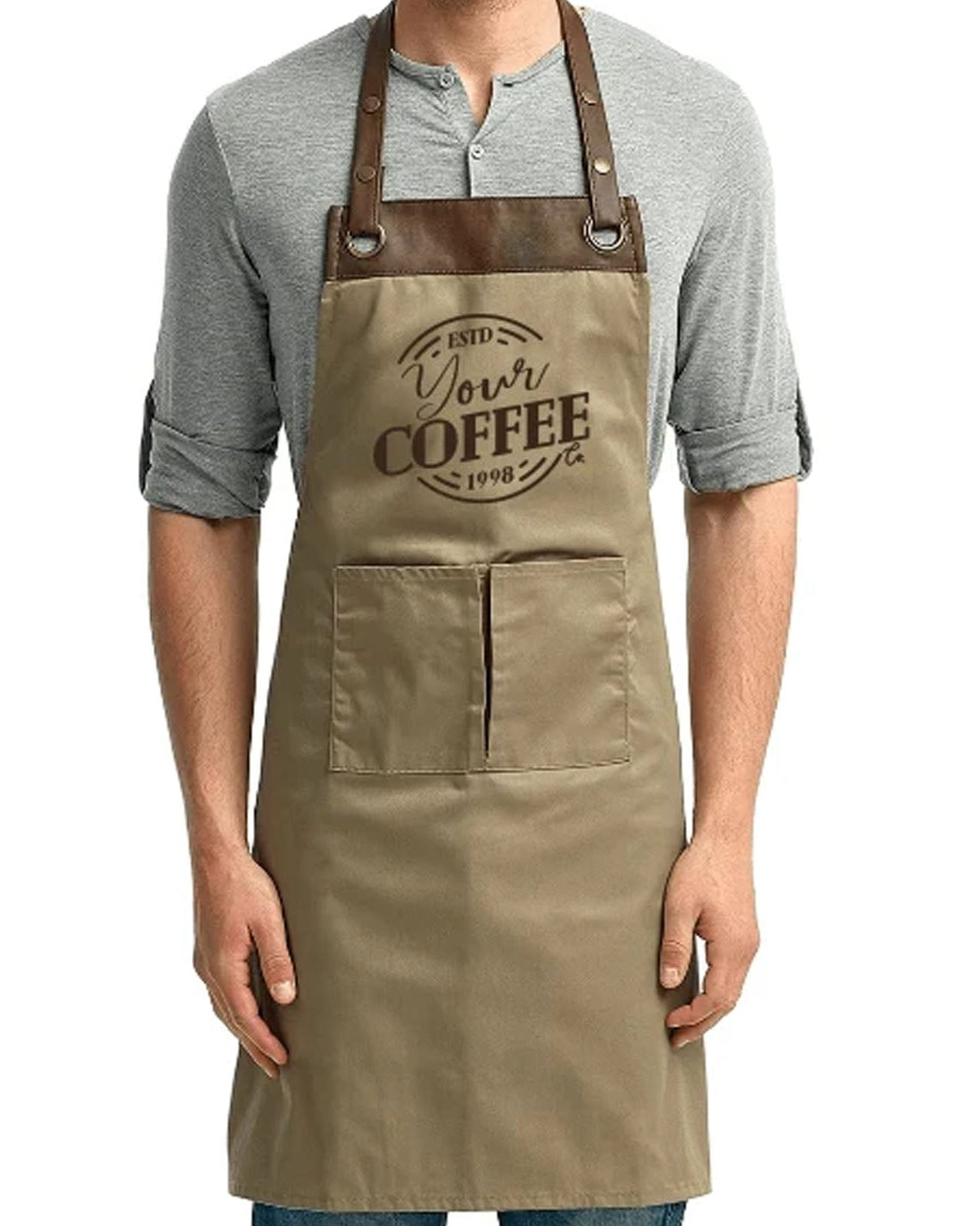 A man wearing a khaki-colored apron with brown leather straps over a gray henley shirt, featuring a printed 'Your Coffee' logo on the chest.