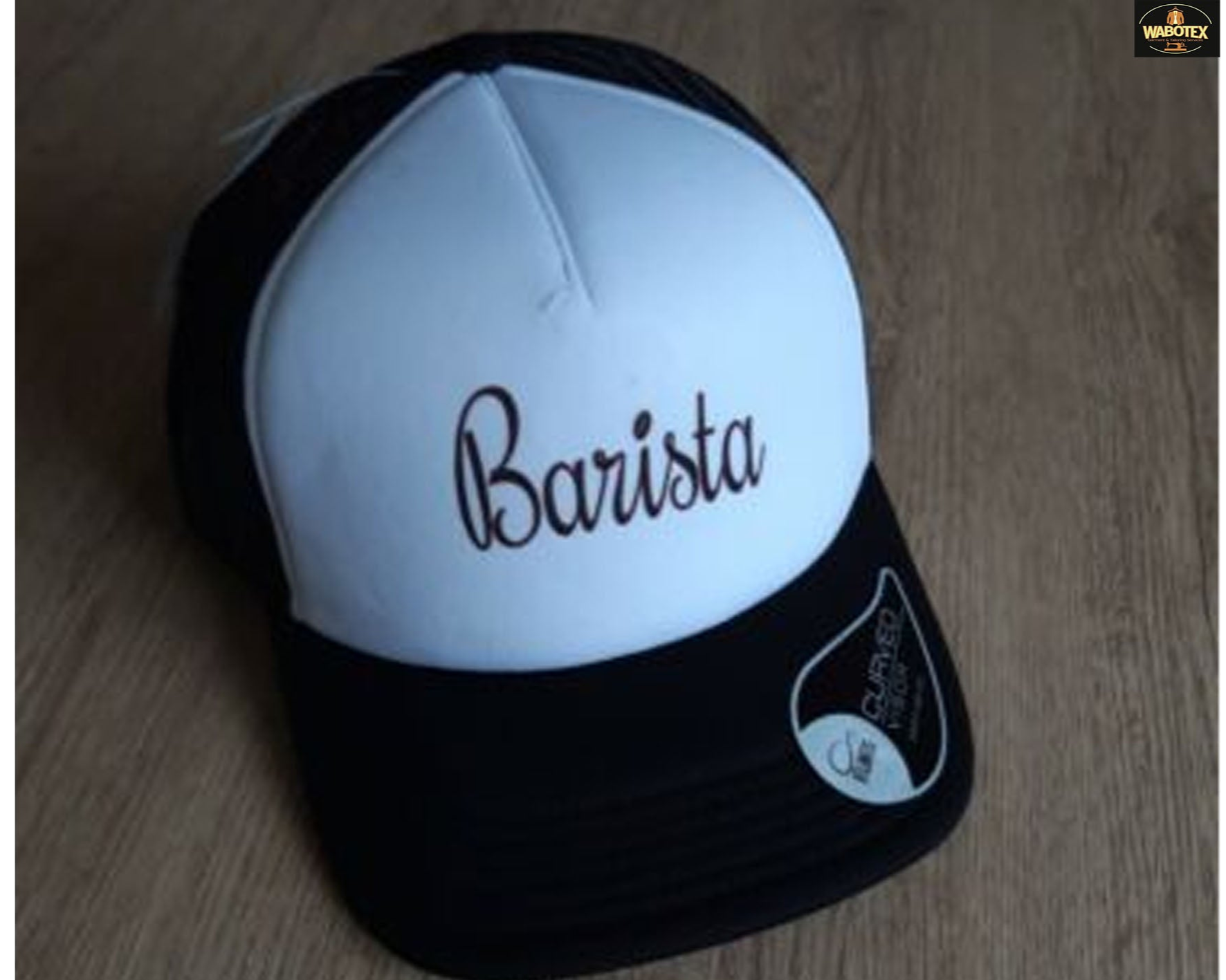 Black and white cap with 'Barista' text on a wooden surface