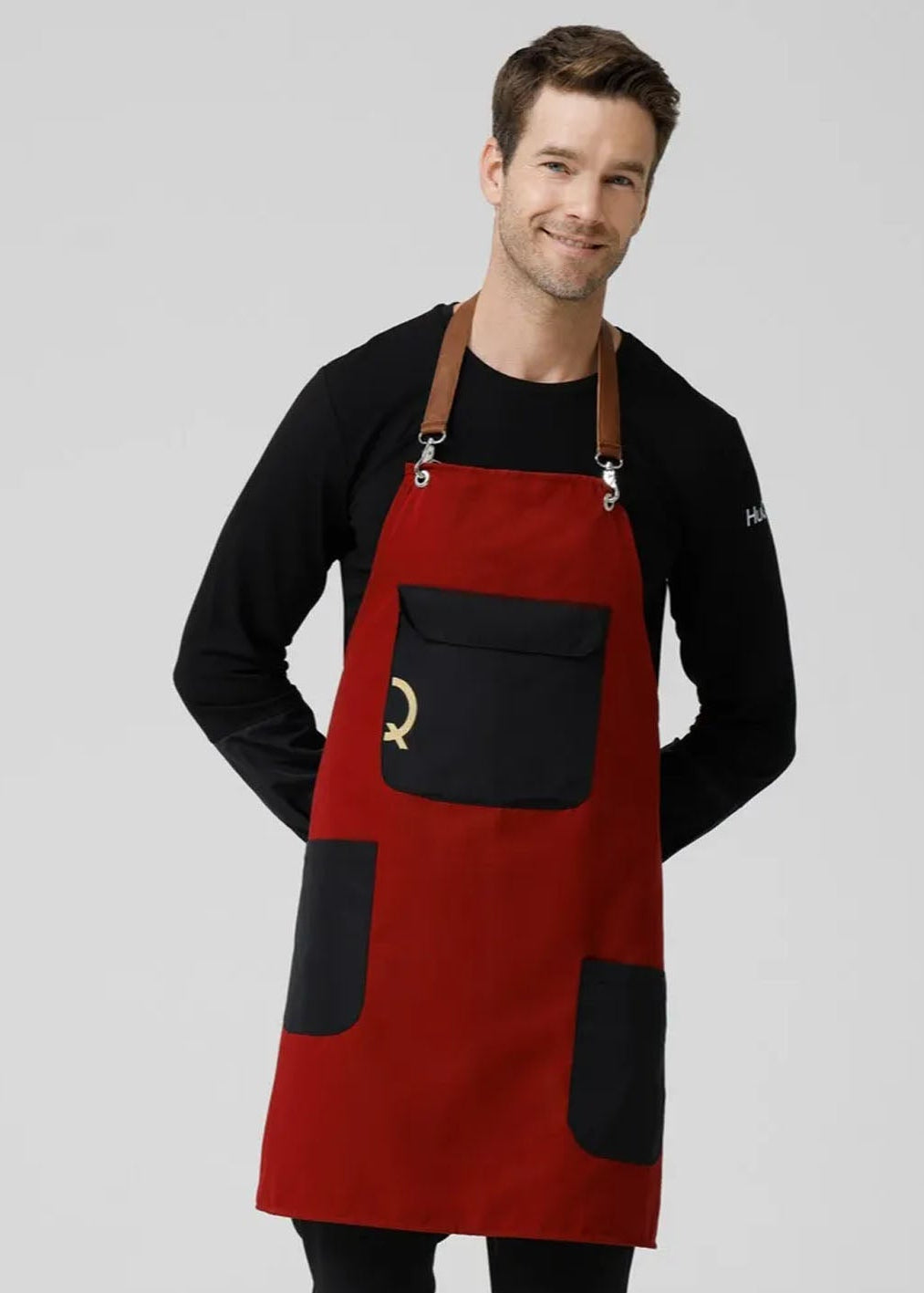 Man wearing a red apron with black pockets on a gray background