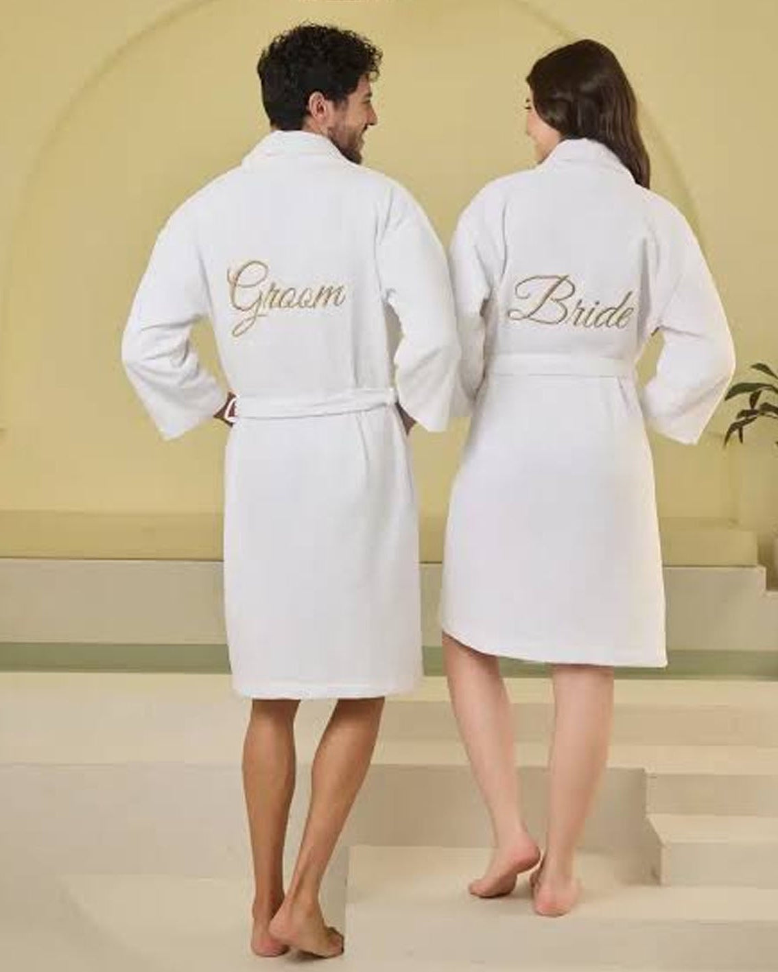 Groom and bride wearing white embroidered bathrobes