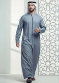 Man wearing a traditional gray outfit with a patterned wall in the background