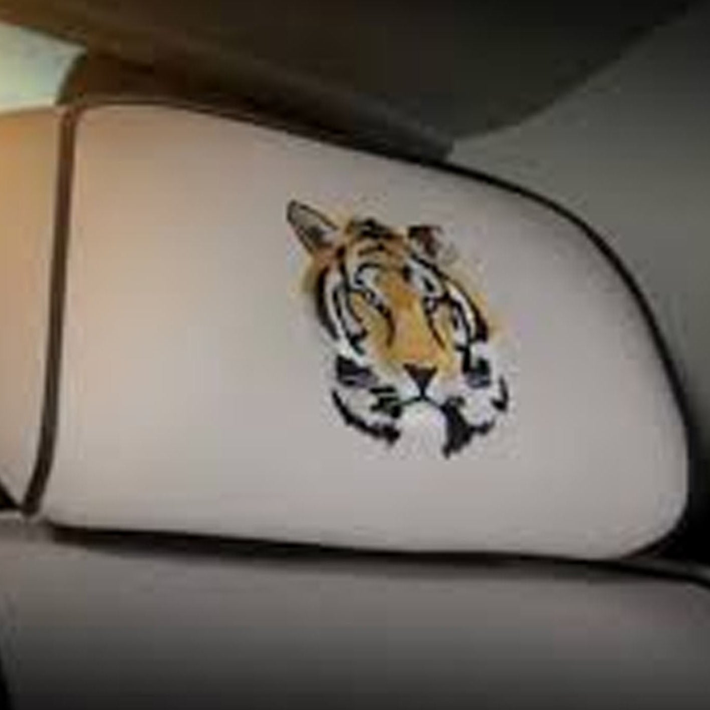 Car headrest cover with tiger design on a gray car interior.