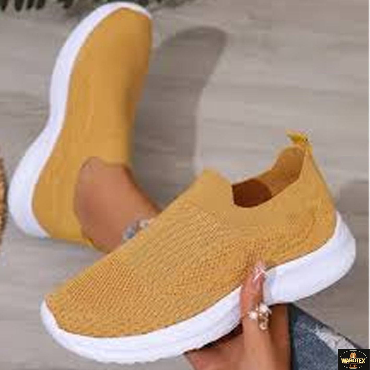 Yellow slip-on sneakers with white soles worn by a person on a light wooden floor.