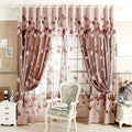 Decorative pink curtains with floral patterns in a room setting.