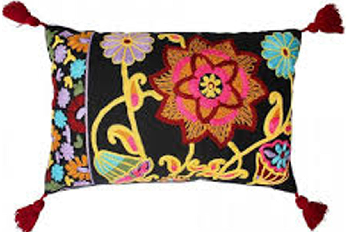 A square decorative throw pillow with a black background and vibrant multicolor floral embroidery, finished with red tassels on the corners, shown against a plain white background.