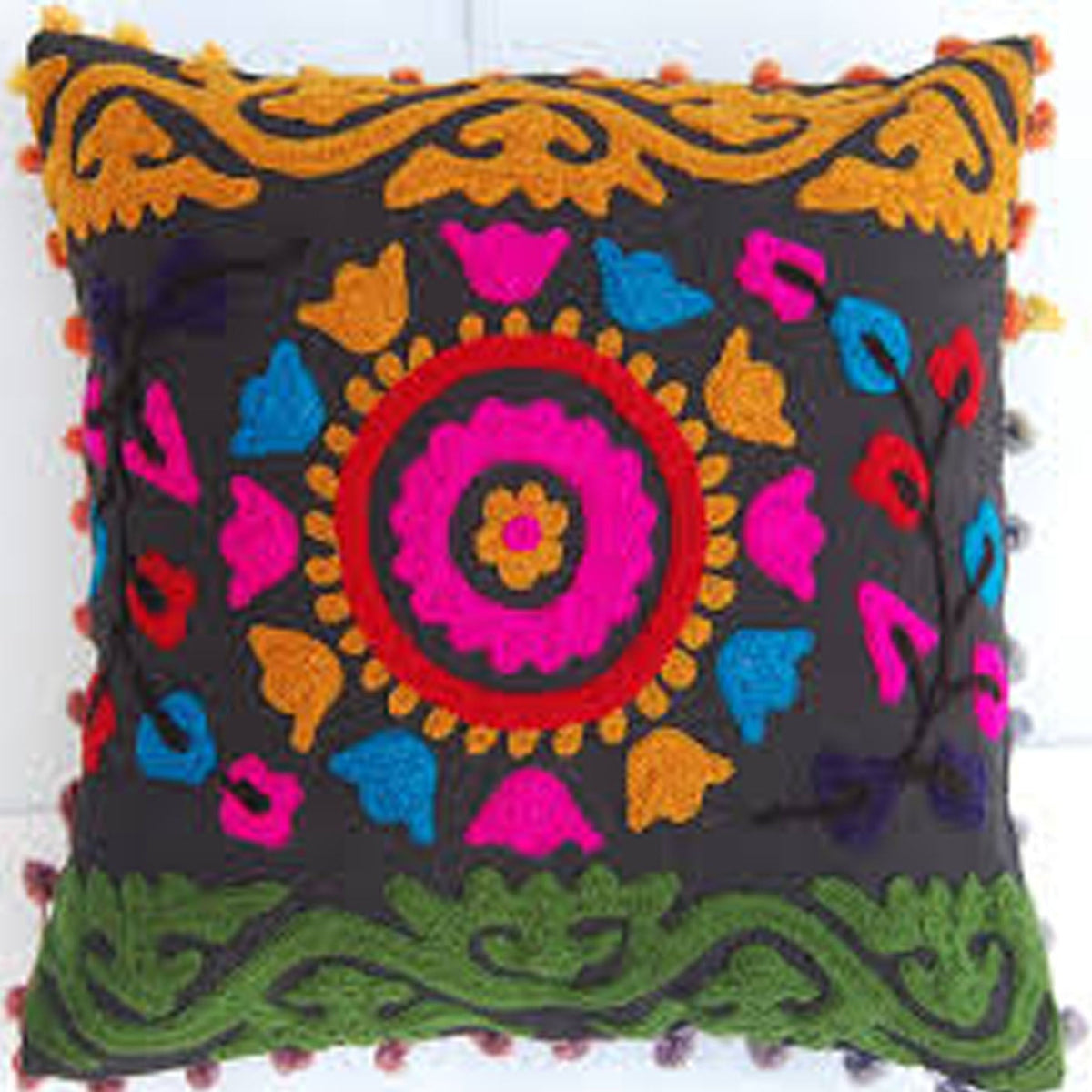 A square black decorative throw pillow featuring a vibrant, colorful hand-embroidered mandala design in pink, red, blue, orange, and green, finished with pom-pom trim along the edges.