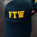 Navy blue cap with 'FTW' in yellow on a wooden surface