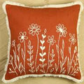Red pillow with white floral embroidery on a beige background