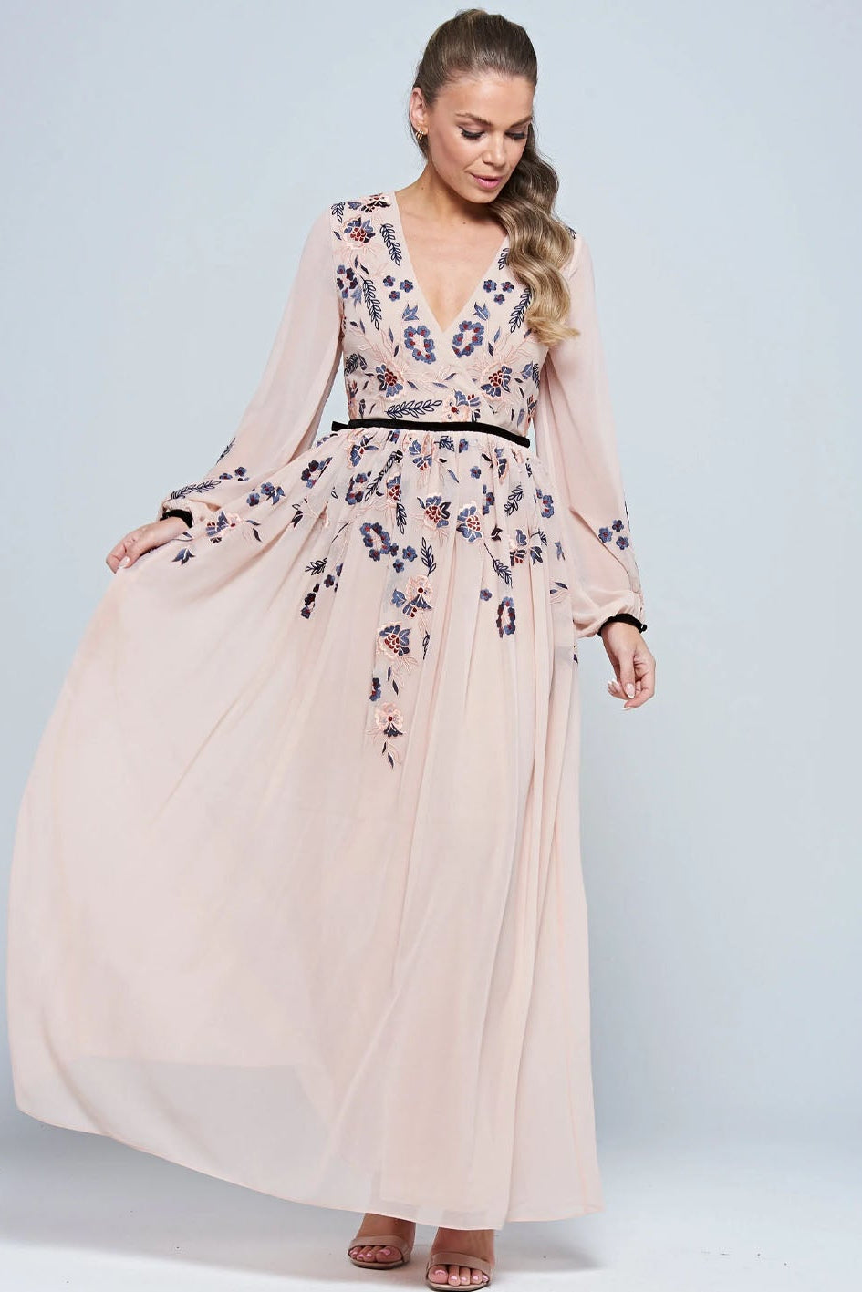 Lady wearing a white dress embroidered with floral design on a blue background
