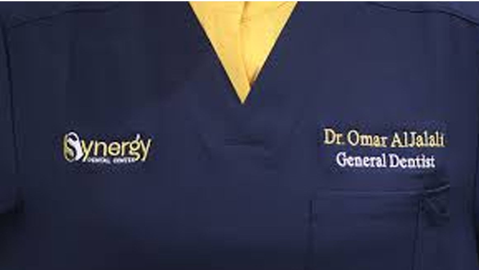 Navy blue scrub top with 'Synergy' logo and 'Dr. Omar Al Jalali General Dentist' text.
