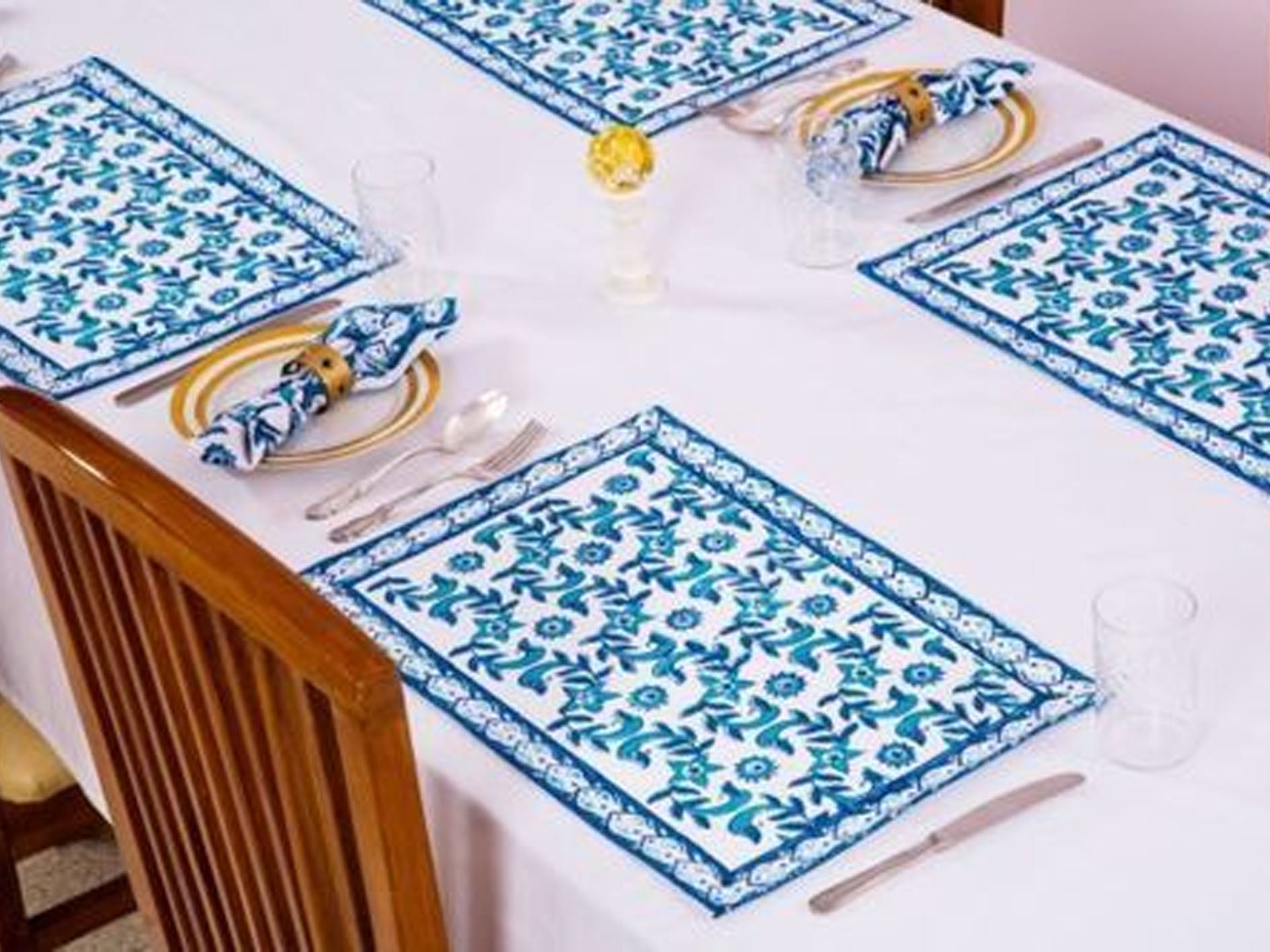 Table setting with blue and white patterned placemats on a white tablecloth.