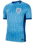 A light blue Nike England soccer jersey with a geometric pattern, featuring the England crest on the chest and a white Nike swoosh on the right side.