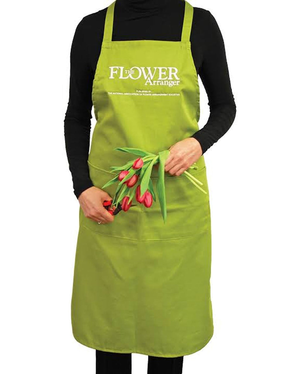 A person wearing a bright green apron over a black long-sleeve shirt, holding a small bouquet of red tulips. The apron has 'FLOWER GARDEN' printed in white on the chest.