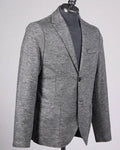 A men's gray textured blazer displayed on a black mannequin torso, layered over a dark gray turtleneck sweater, against a light gray background.