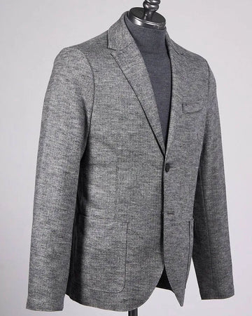 A men's gray textured blazer displayed on a black mannequin torso, layered over a dark gray turtleneck sweater, against a light gray background.