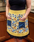 Person wearing a floral apron with yellow accents in a kitchen setting