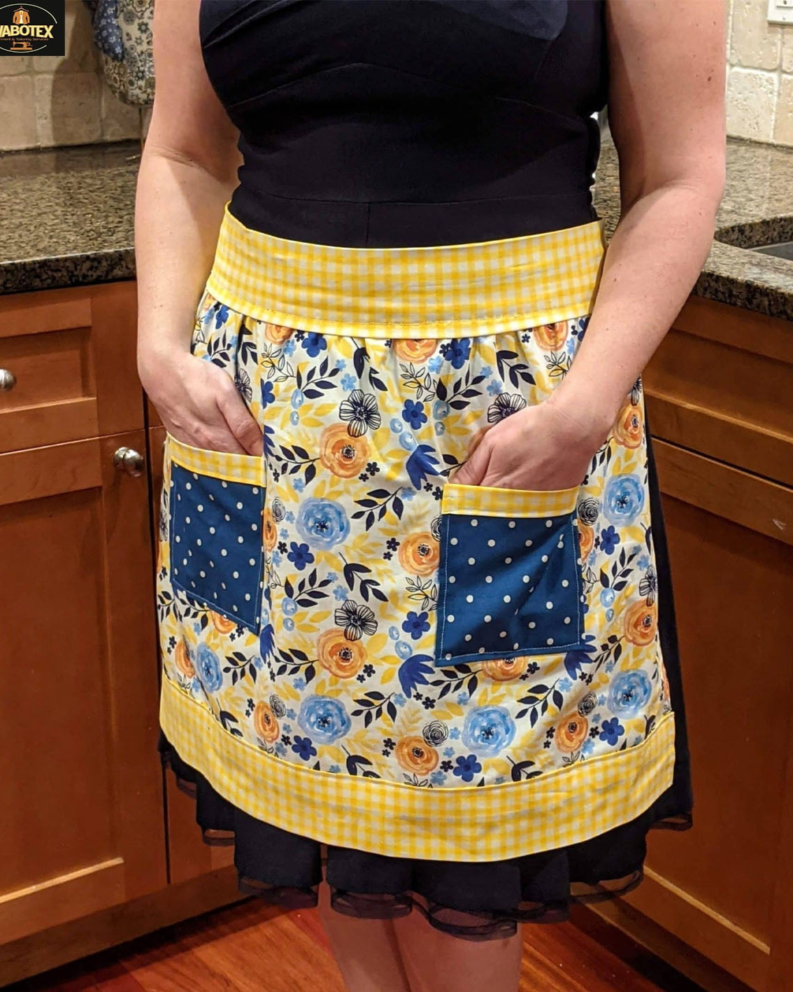Person wearing a floral apron with yellow accents in a kitchen setting
