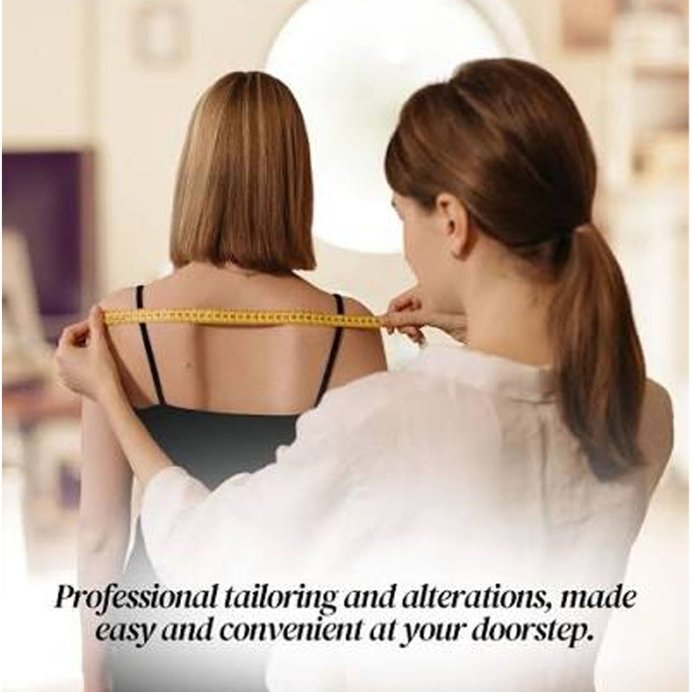 A woman in a white blouse measures the back of another woman wearing a black camisole with a yellow measuring tape. Text at the bottom reads, 'Professional tailoring and alterations, made easy and convenient at your doorstep.