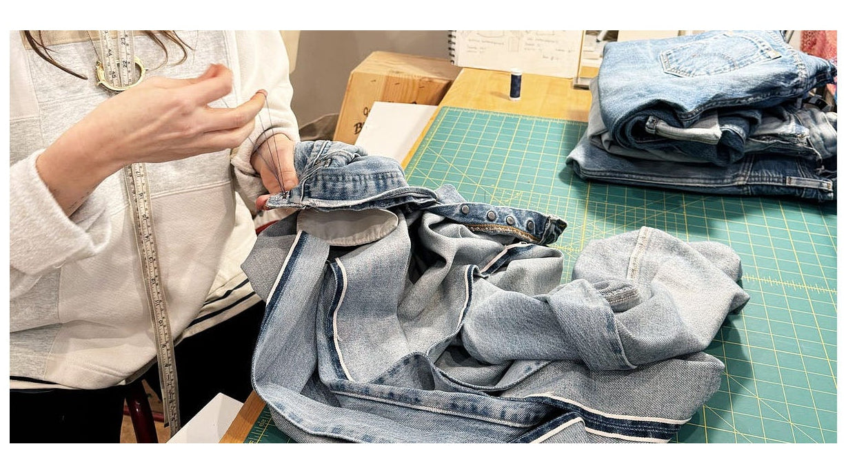 Person sorting through folded clothes on a table with a white background