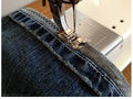 Sewing machine stitching a piece of denim fabric.