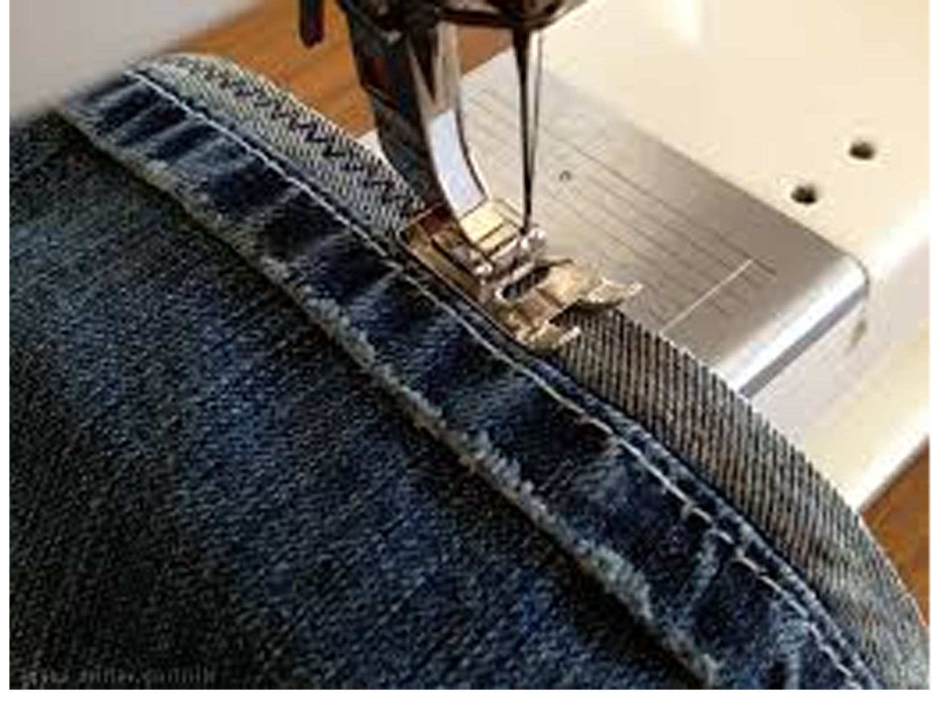 Sewing machine stitching a piece of denim fabric.