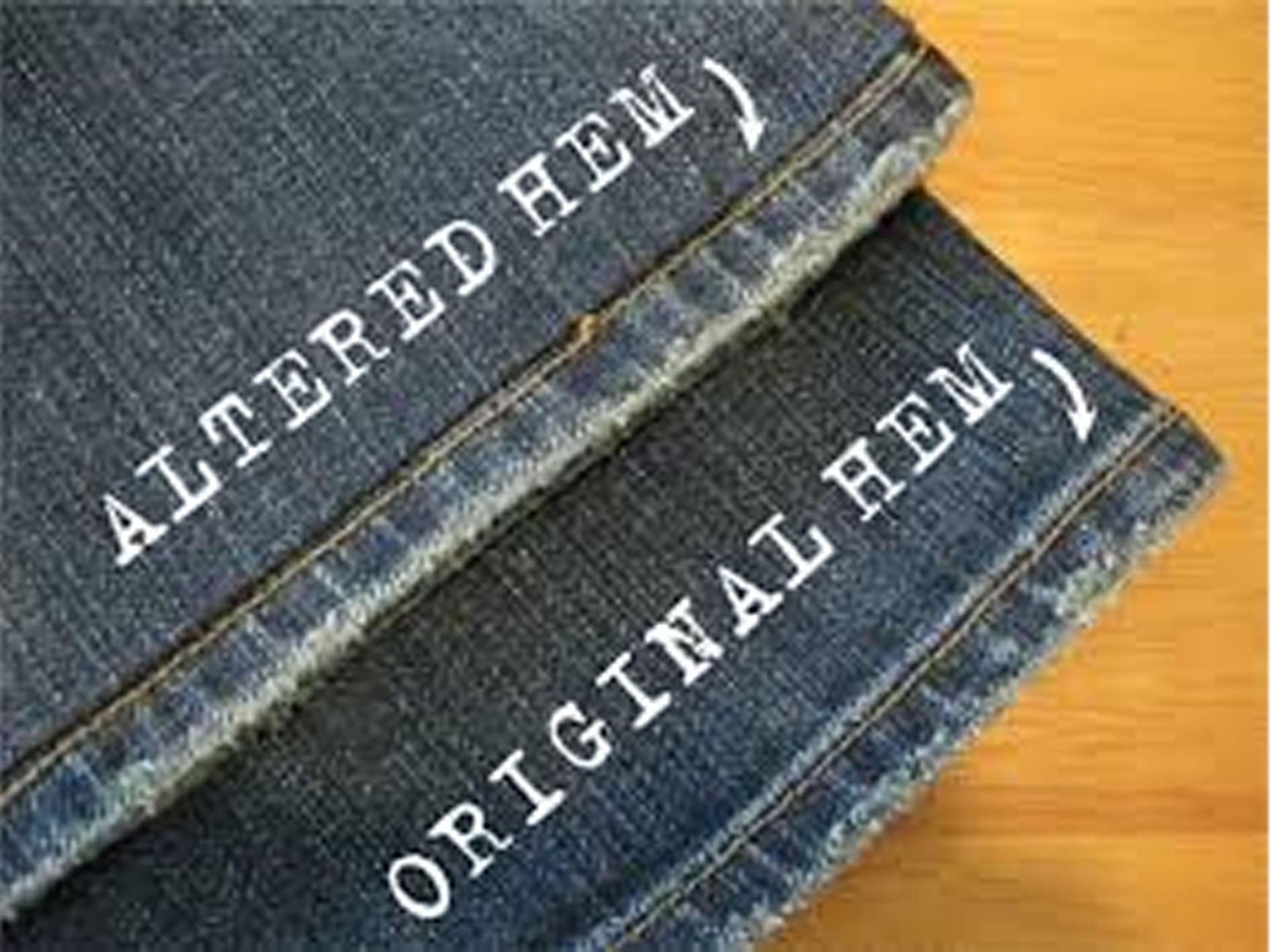 Two pairs of jeans with 'Altered Hem' and 'Original Hem' labels on a wooden surface.