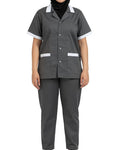 A person wearing a dark gray short-sleeve scrub top with white trim on the collar and sleeve cuffs, paired with matching dark gray scrub pants, shown against a plain white background.