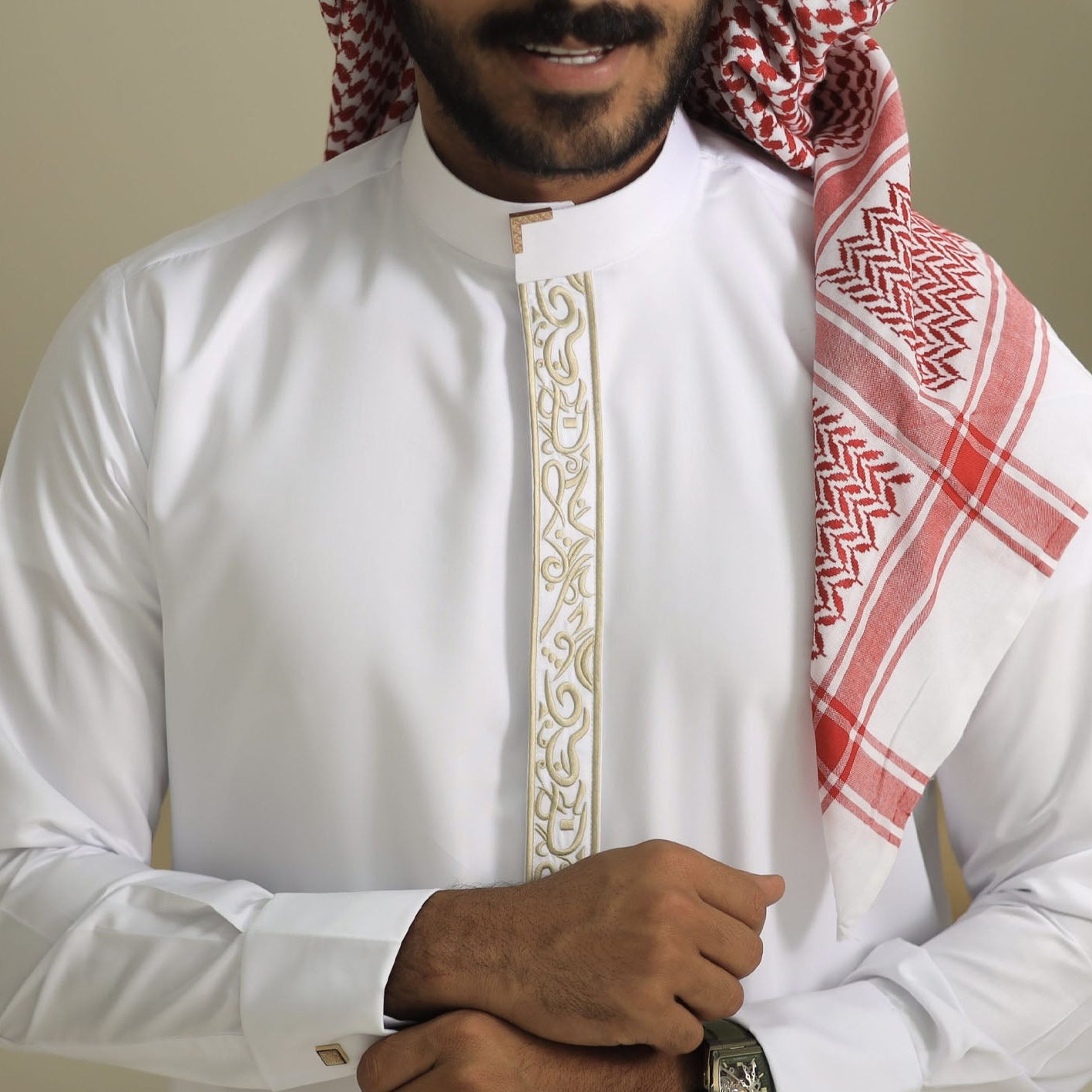 Man wearing a white embroidered shirt with a red and white patterned scarf