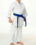 A child wearing a white martial arts gi with a bright blue belt, standing barefoot against a plain white studio background.