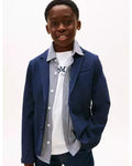 A young boy modeling a navy blue blazer over a white t-shirt and a blue-and-white striped button-up shirt, set against a plain white background.