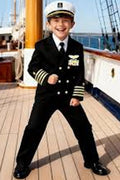 Child in a captain's outfit on a ship deck with ocean view