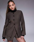 Woman wearing a brown blazer and skirt set against a gray background