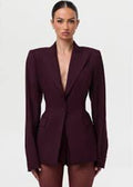 Woman wearing a burgundy blazer dress on a white background