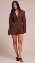 Woman wearing a brown blazer dress against a neutral background