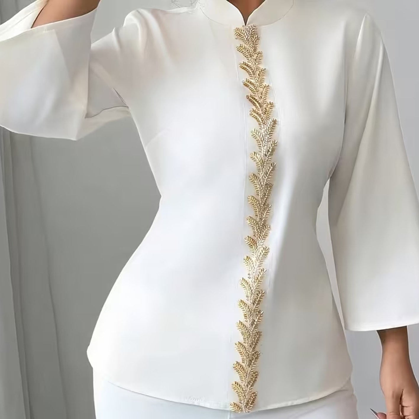 White outfit with gold embroidery on a plain background