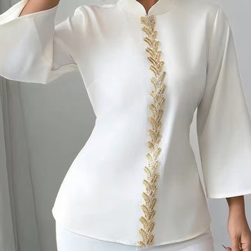 White outfit with gold embroidery on a plain background