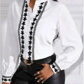 White blouse with black embroidery and black pants on a white background