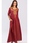 Woman wearing a long maroon dress with gold patterns on a white background