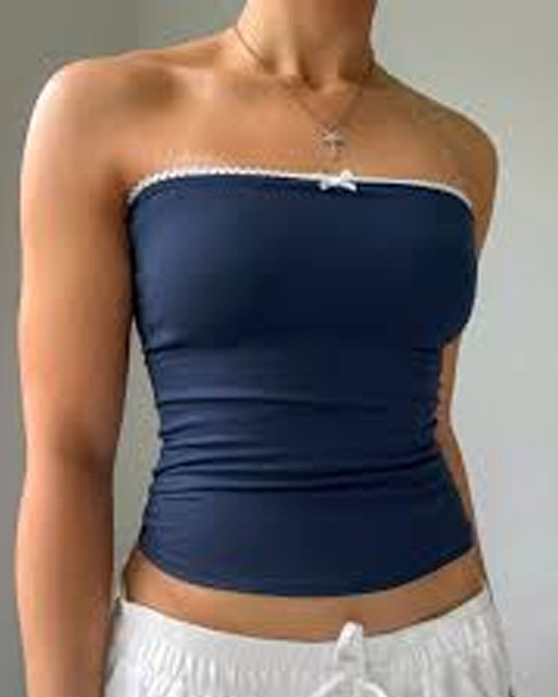 Navy blue strapless top worn by a person on a plain background