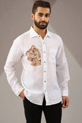 A man weraing a white linen shirt with a bear embroidered