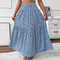 Person wearing a blue floral skirt in a room with white walls and furniture.