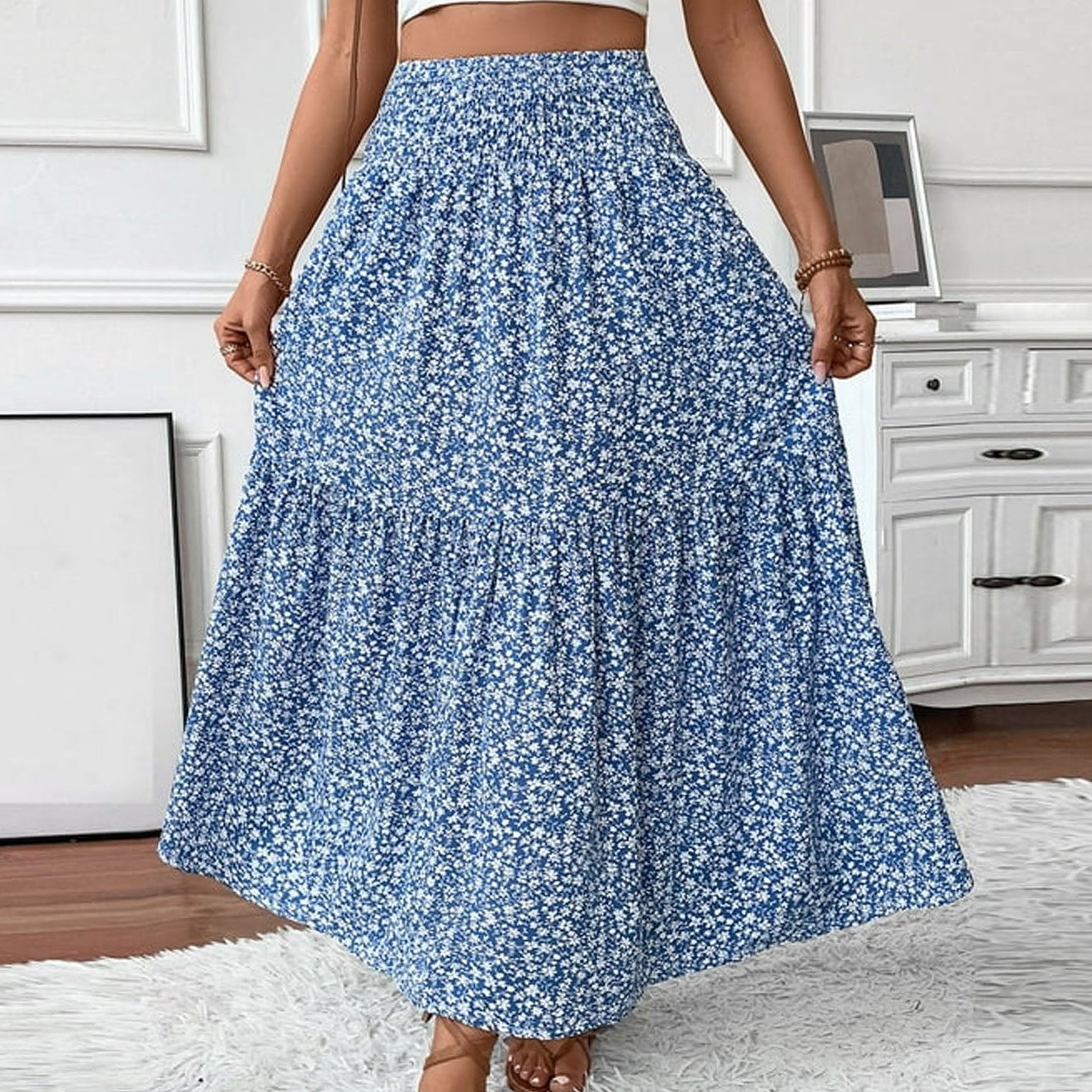 Person wearing a blue floral skirt in a room with white walls and furniture.